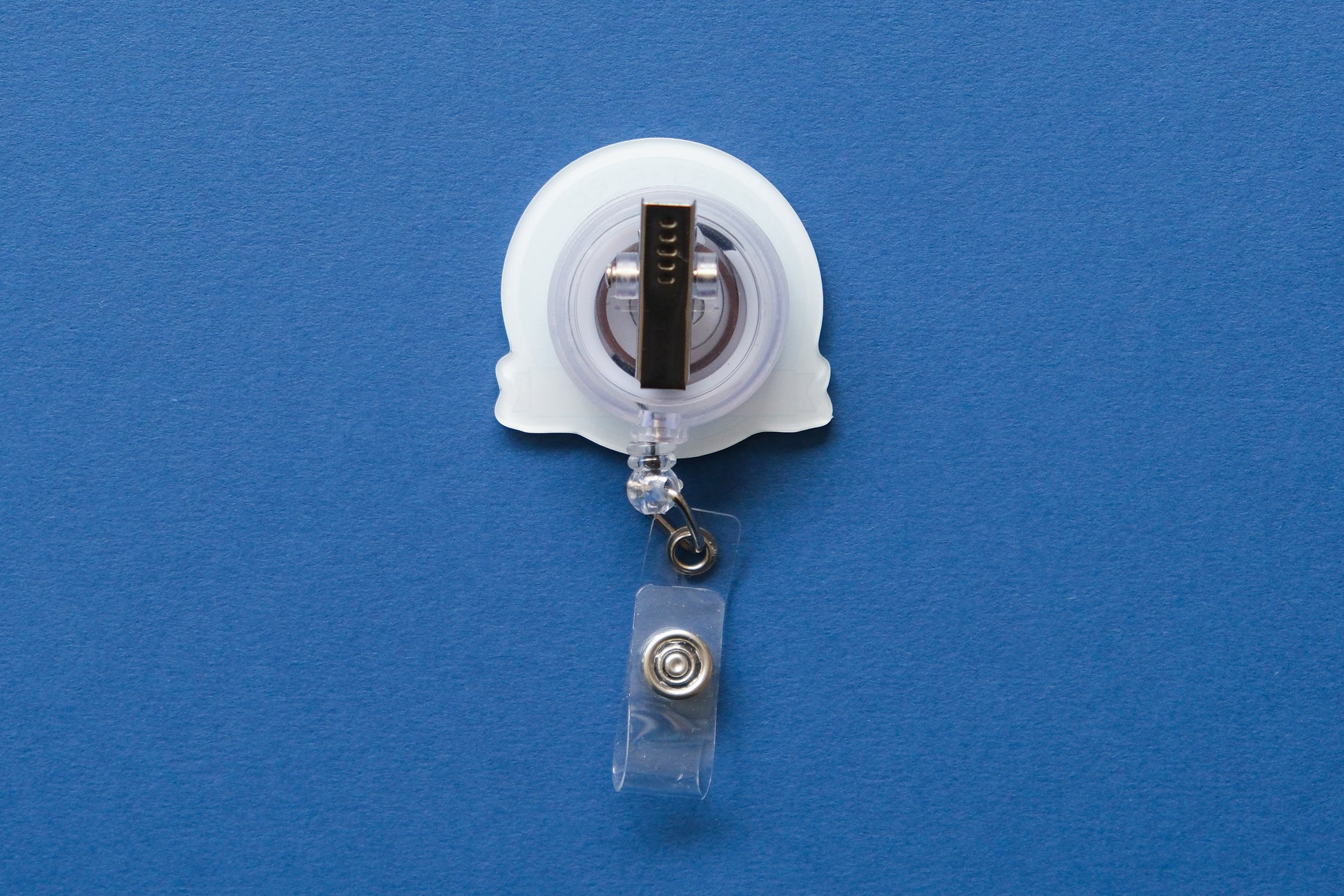A retractable badge reel with a clear plastic clip and a white acrylic badge, shown against a solid blue background.