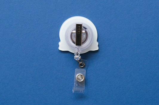 A retractable badge reel with a clear plastic clip and a white acrylic badge, shown against a solid blue background.