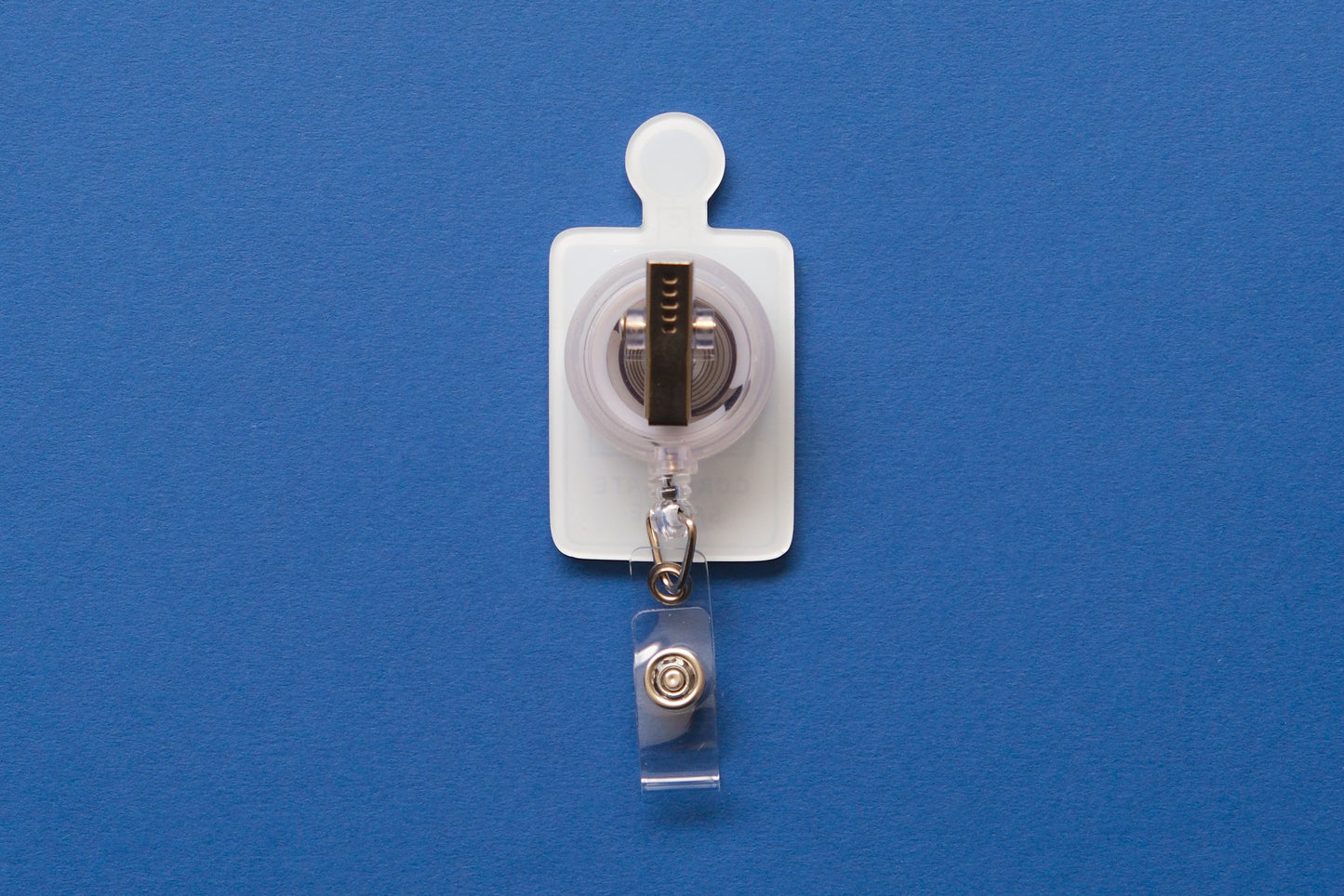 Photo of an acrylic badge reel shaped like a corporate badge that says "Corporate Saddie" over a dark blue background.