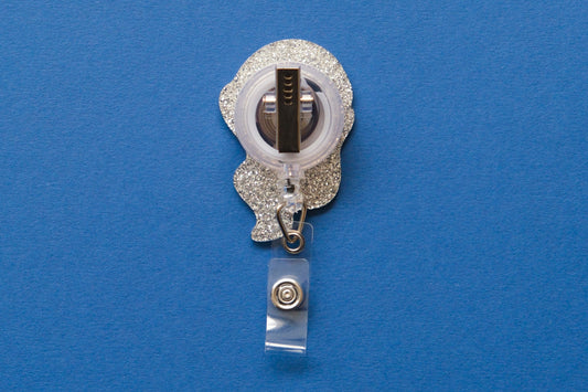 Photo of the back of an acrylic badge reel with an alligator clip over a dark blue background.