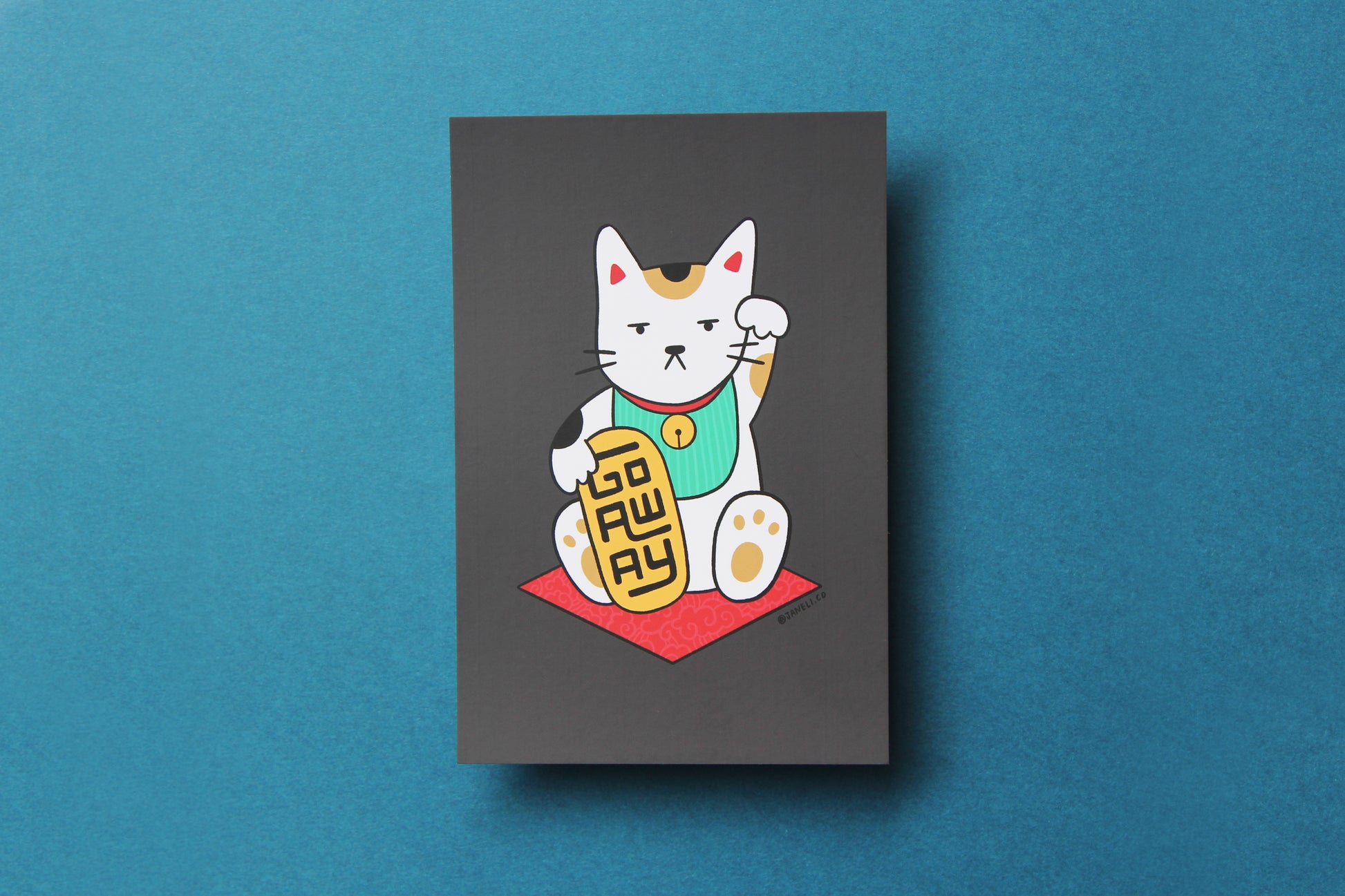 A JaneLi.Co mini print/postcard that shows a maneki neko cat holding a gold bar that says "Go Away" over a teal background.