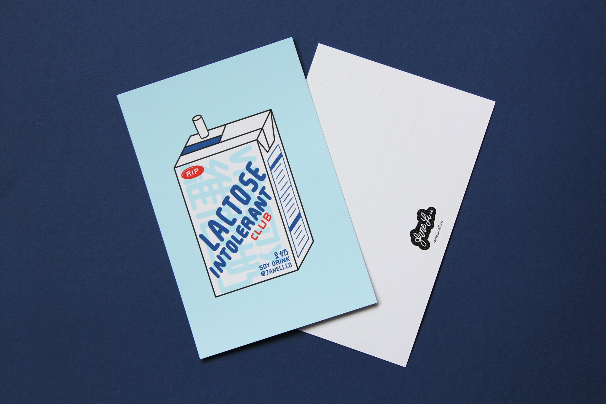 A JaneLi.Co mini print/postcard of a soymilk carton that says "Lactose Intolerant Club" and a back postcard side of the same print over a navy background.
