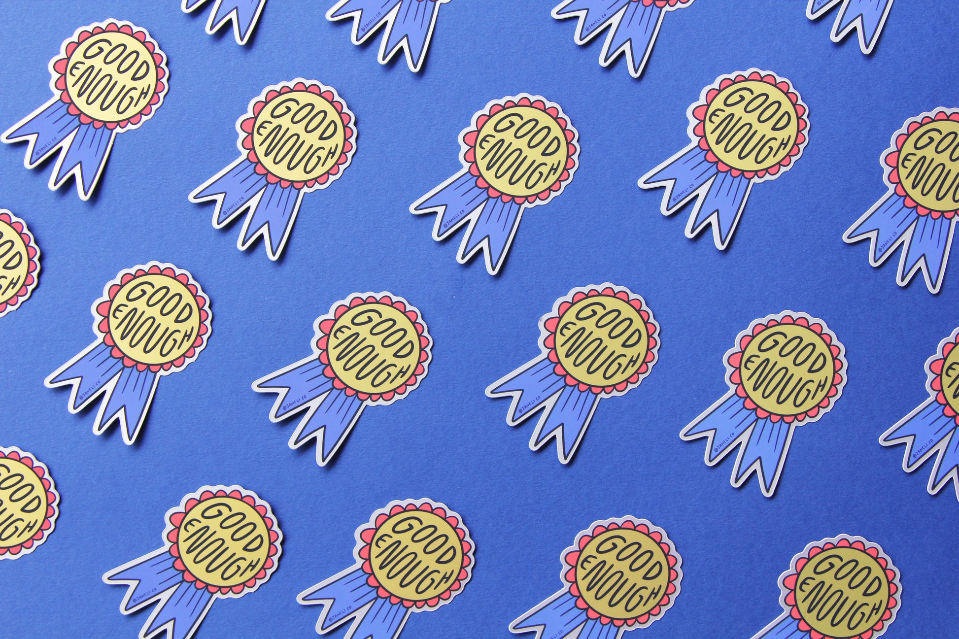 A grid of JaneLi.Co stickers of red and blue award ribbons that say "Good Enough" over a blue background.