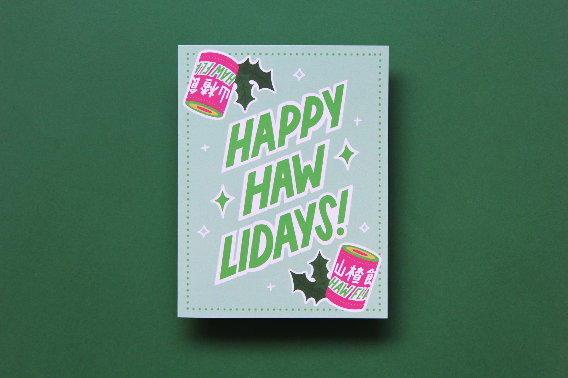 A photo of a greeting card with haw flakes and lettering that says "Happy Haw-lidays!" on a green background.