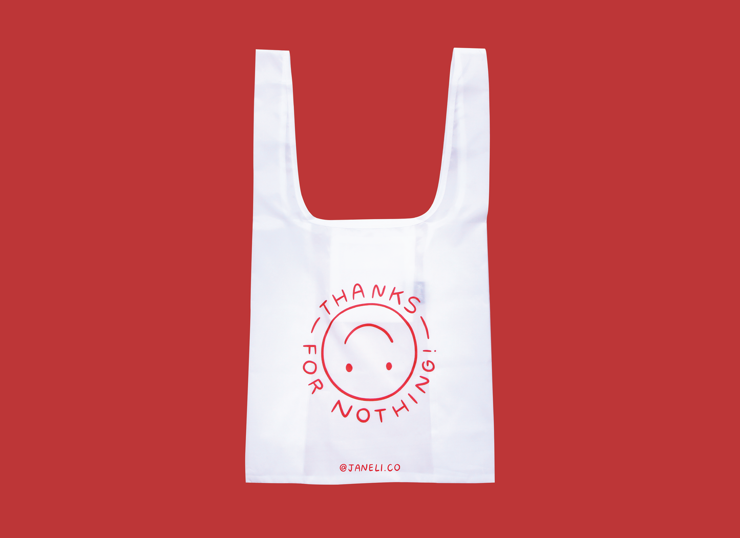A photo of a white foldable grocery bag with an upside down smiley face that says "Thanks for nothing" over a red background.