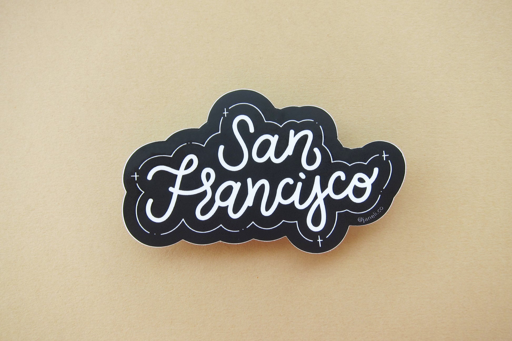 A black and white JaneLi.Co sticker that says "San Francisco" in cursive lettering over a tan background. 