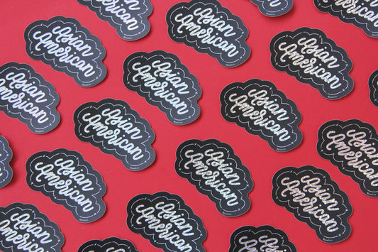 A grid of black and metallic glitter JaneLi.Co stickers that say "Asian American" in cursive lettering over a red background.