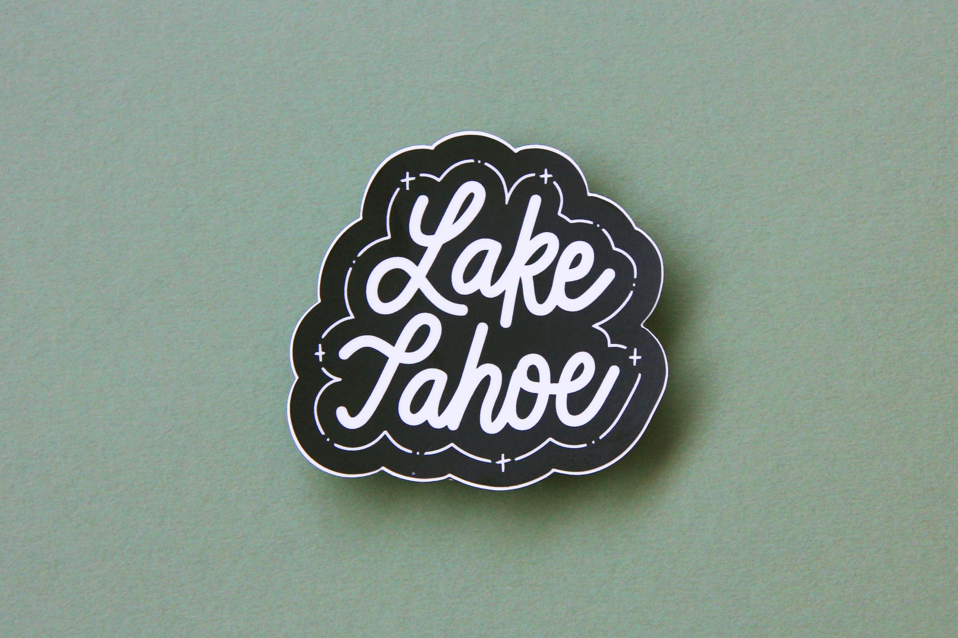 A black and white JaneLi.Co sticker that says "Lake Tahoe" in cursive lettering over a green background. 
