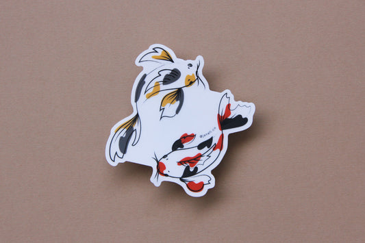 A JaneLi.Co sticker of a gold and grey koi fish and a scarlet and black koi fish swimming in a circle over a tan background. 