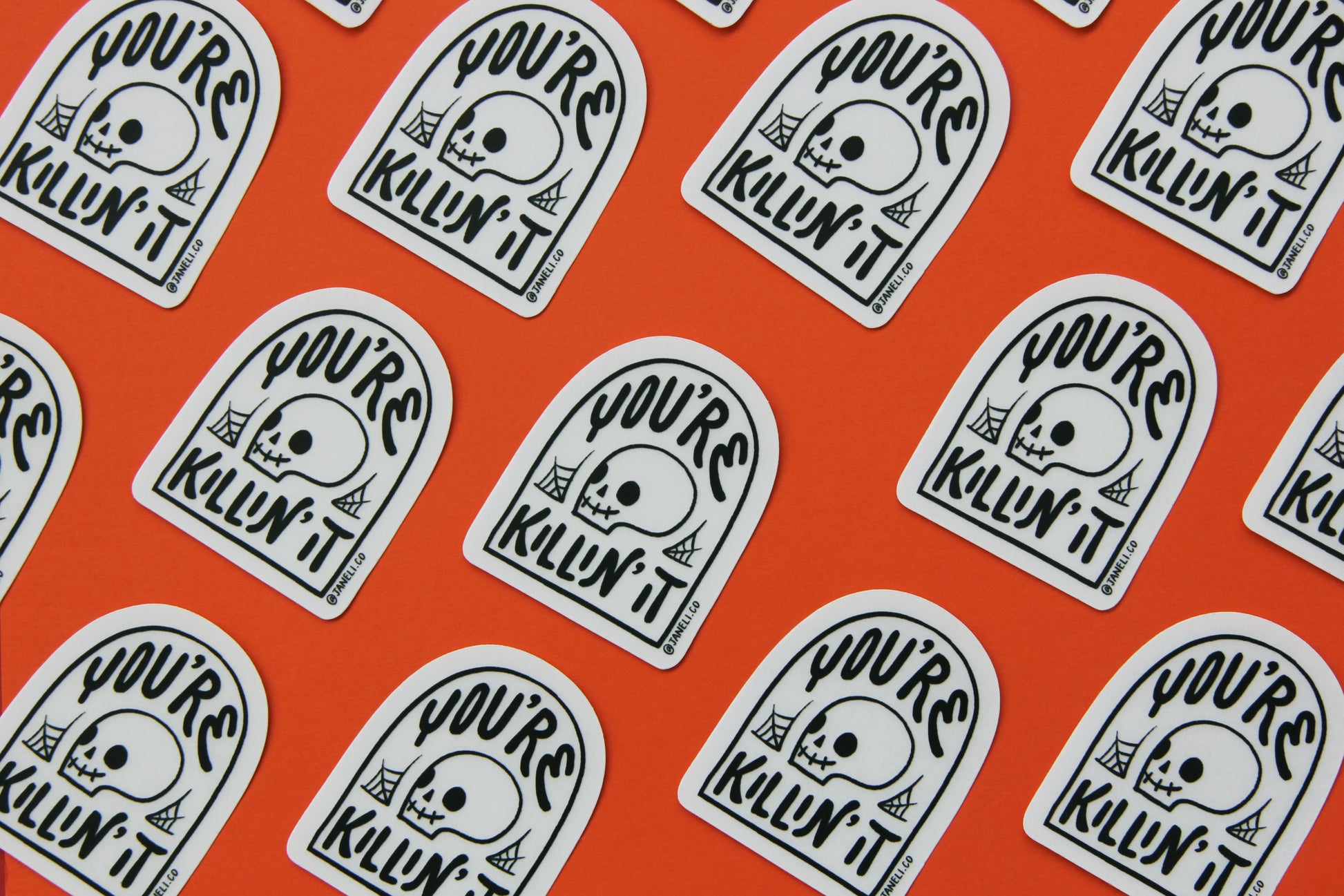 A grid of JaneLi.Co stickers that say "You're Killin' It" in the shape of tombstones with skulls in them over an orange background.