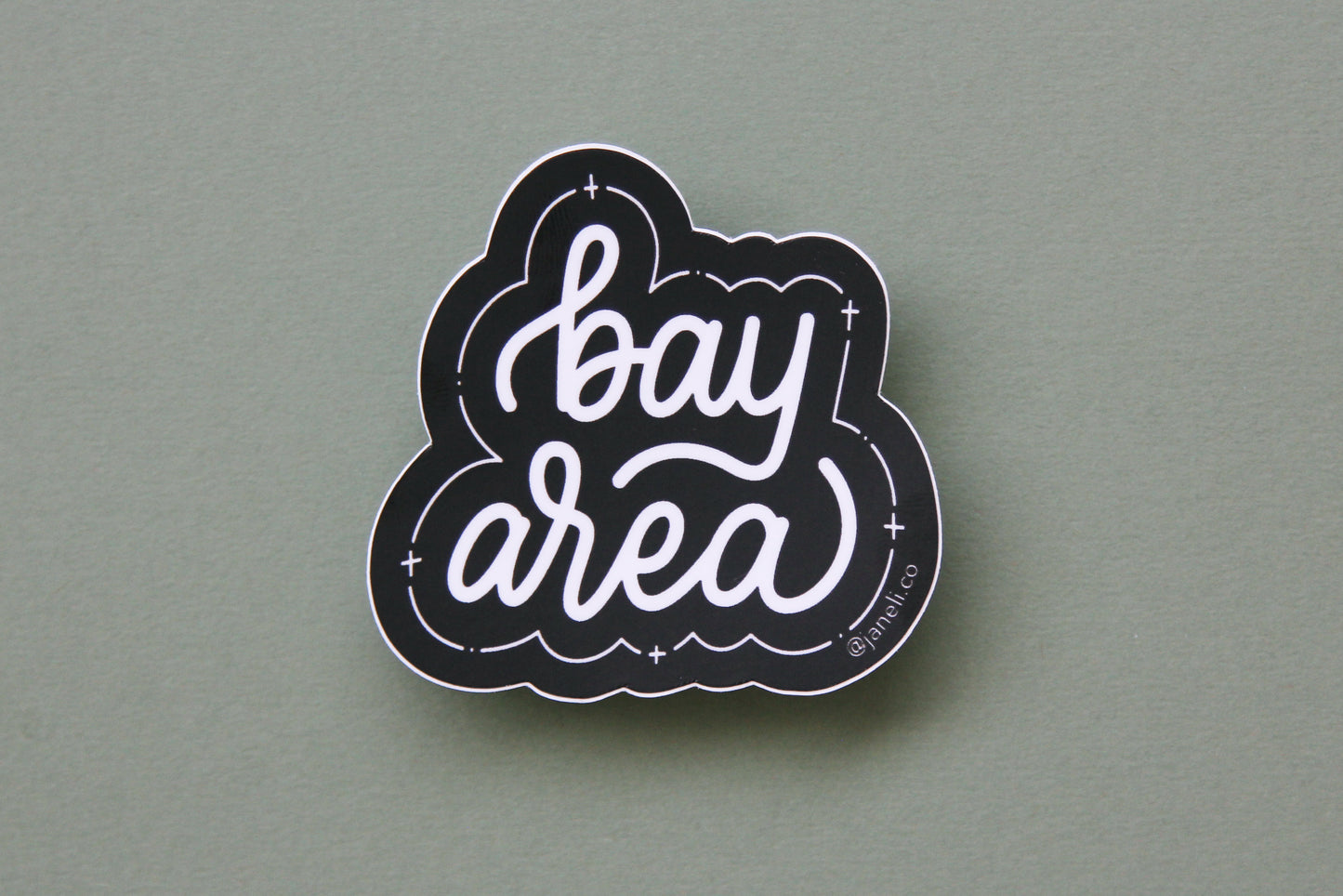 A black and white JaneLi.Co sticker that says "Bay Area" in cursive lettering over a green background. 
