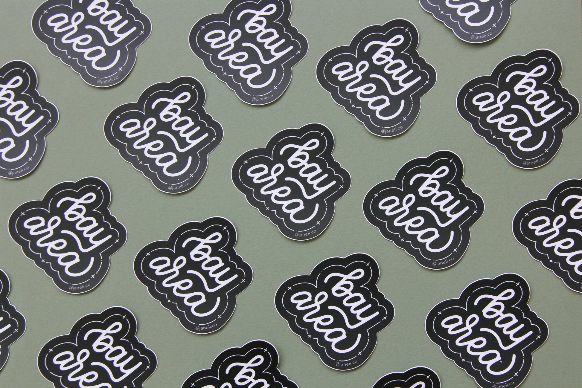 A grid of black and white JaneLi.Co stickers that say "Bay Area" in cursive lettering over a green background. 
