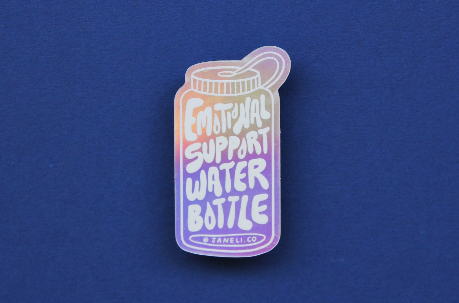 A holographic JaneLi.Co sticker that says "Emotional Support Water Bottle" in the shape of a water bottle over a navy blue background.