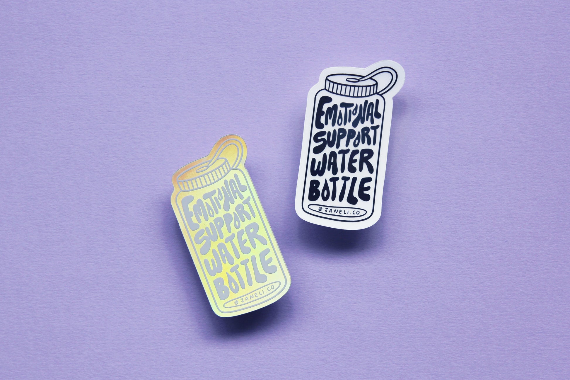 Two JaneLi.Co stickers that say "Emotional Support Water Bottle" in the shape of a water bottle over a lavender background. One sticker is black and white, and the other is holographic.