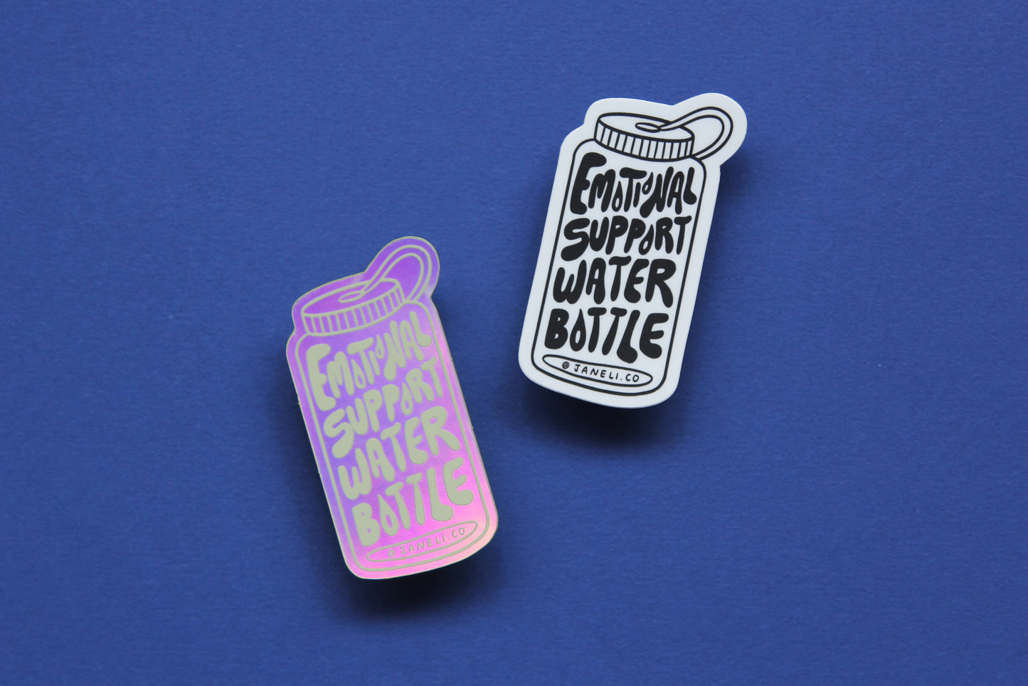 Two JaneLi.Co stickers that say "Emotional Support Water Bottle" in the shape of a water bottle over a navy blue background. One sticker is black and white, and the other is holographic.