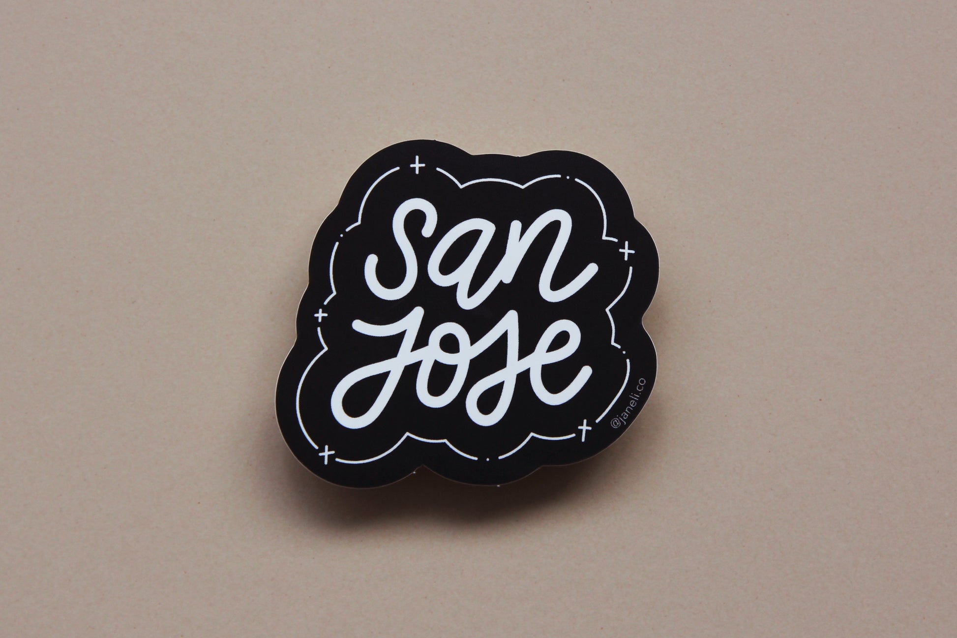 A black and white JaneLi.Co sticker that says "San Jose" in cursive lettering over a tan background. 
