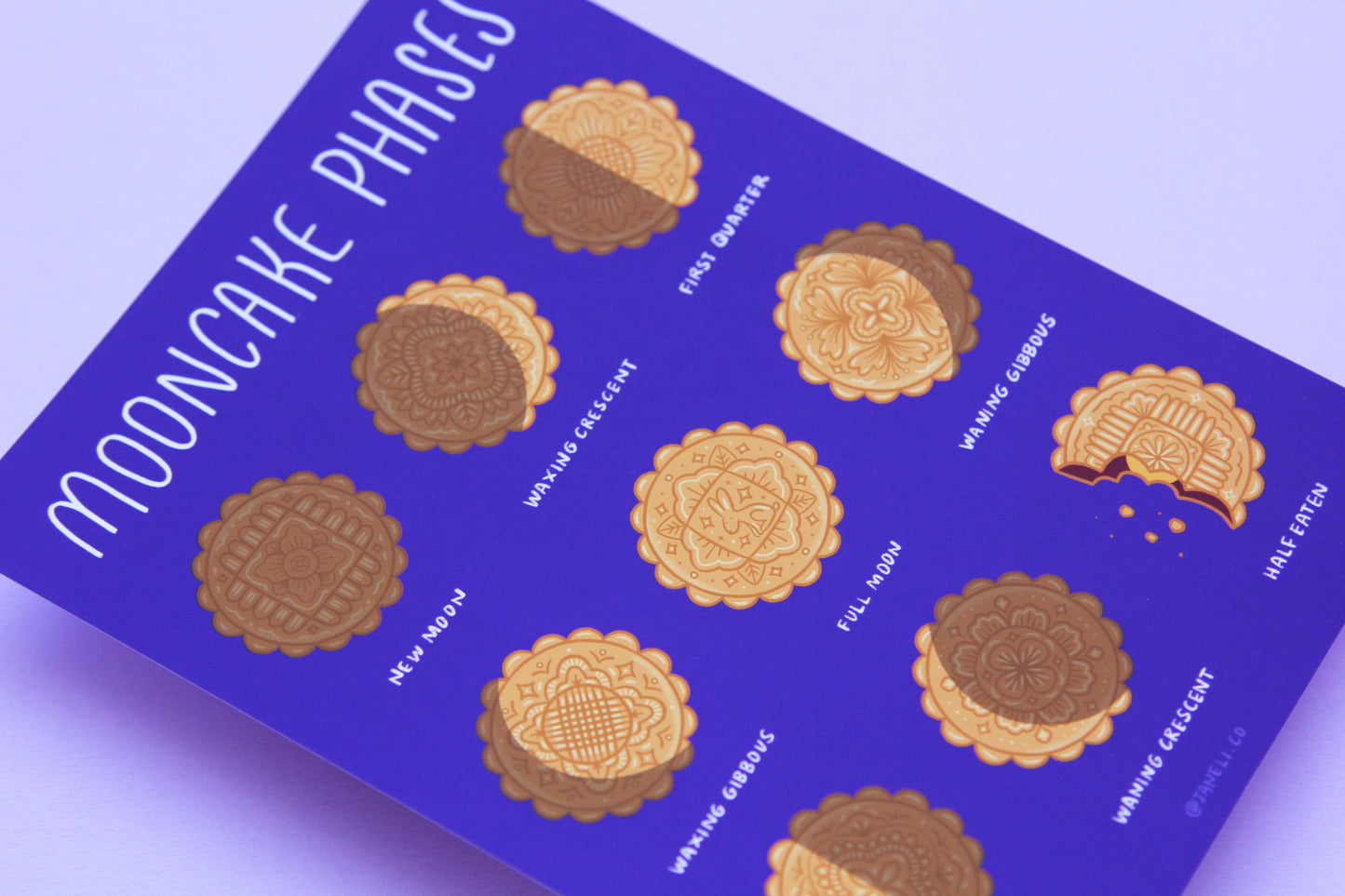 A close up of a JaneLi.Co print that says "Mooncake Phases" with 9 different illustrations of mooncakes in the different moon cycle phases over a purple background.