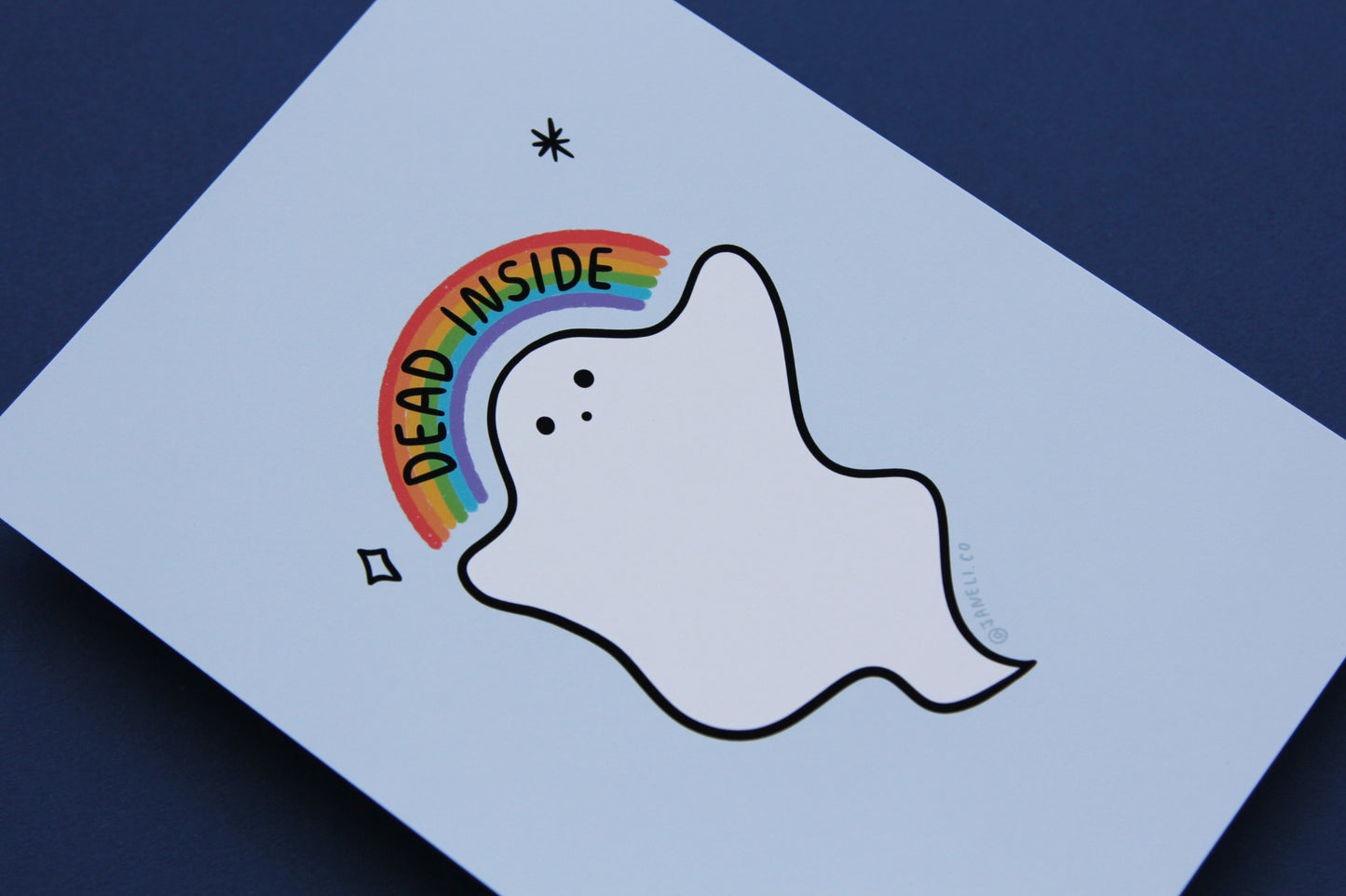 A close up of a JaneLi.Co print that shows a little white ghost holding up a rainbow that says "Dead Inside" over a navy blue background.