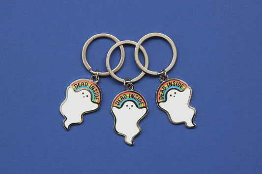 3 enamel keychains showing a little white ghost holding a rainbow that says "Dead Inside" over a navy background.