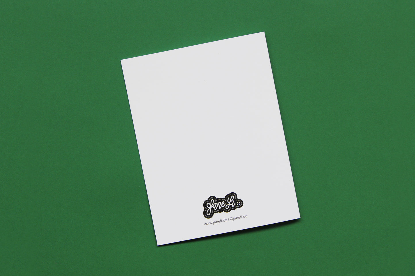 A photo of the blank back of a greeting card on a green background.