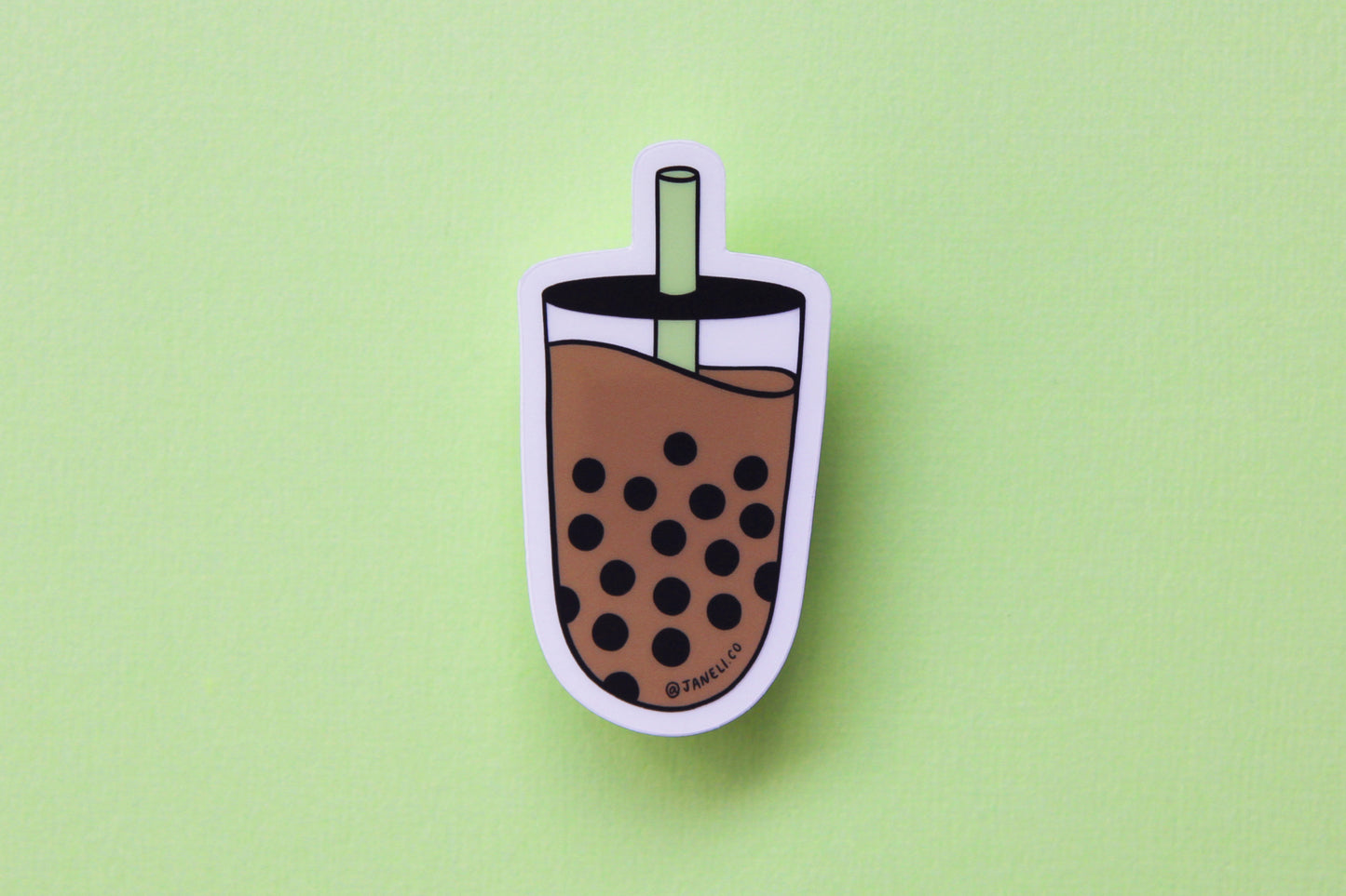 A JaneLi.Co sticker showing a cup of a boba with a green straw over a green background.