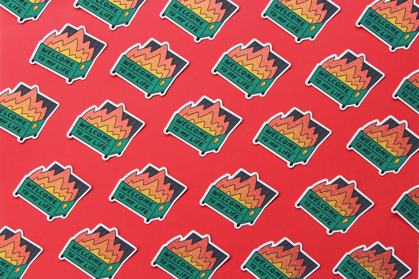 A grid of JaneLi.Co stickers that say "Welcome to my life" in the shape of a dumpster on fire over a red background.