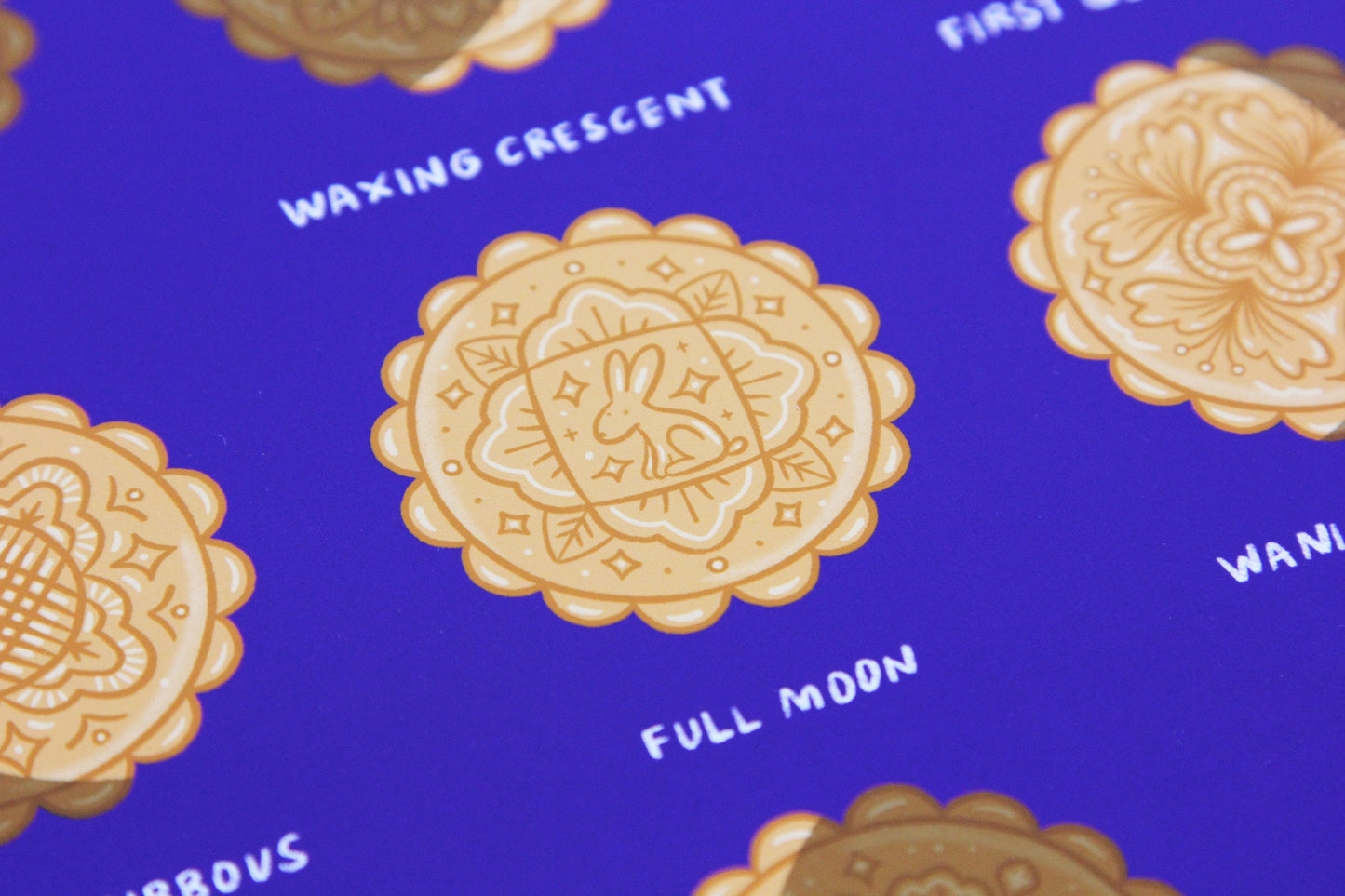 A close up of a JaneLi.Co print that says "Mooncake Phases" with 9 different illustrations of mooncakes in the different moon cycle phases.
