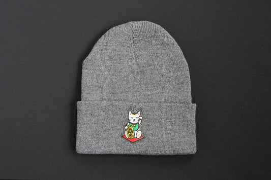 A cuffed charcoal grey beanie with an embroidered maneki neko cat holding a gold bar that says "Go Away" on a black background. 